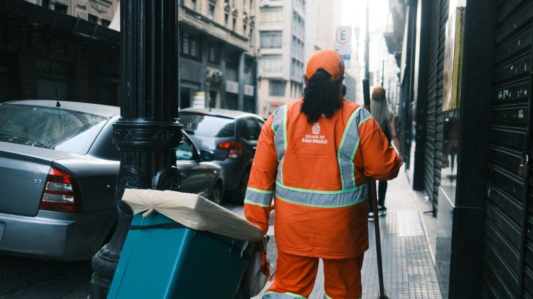 Desemprego cai para 5,3% e Brasil cria 165,8 mil vagas formais em agosto Trabalhador da limpeza urbana carrega equipamentos enquanto caminha por uma rua de São Paulo.