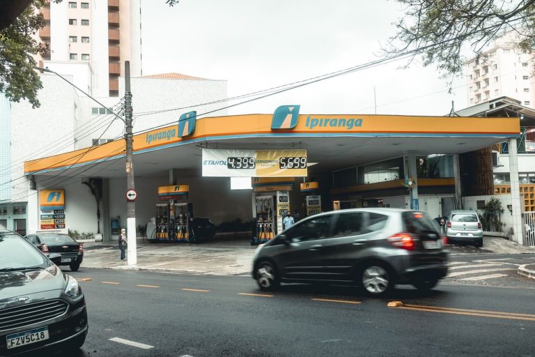 Posto de combustíveis Ipiranga com veículos circulando em uma movimentada rua urbana.