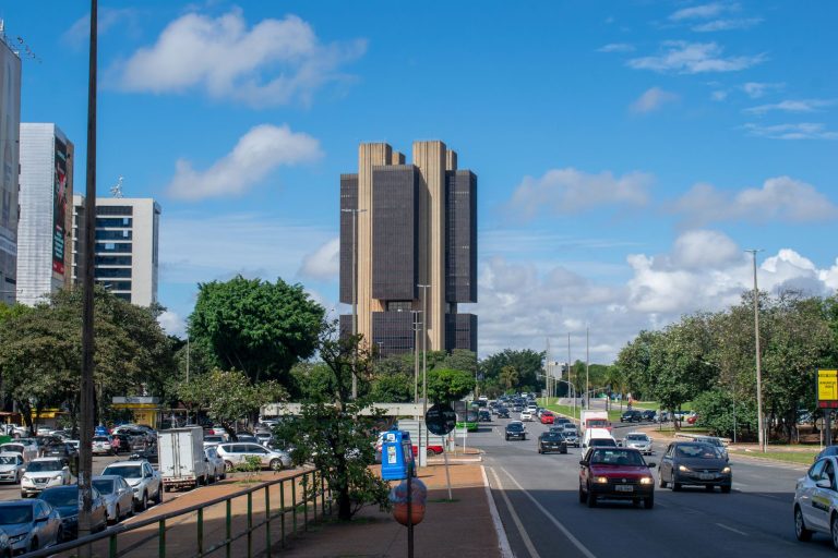 Ata do Copom mantém cautela após corte da Selic para 13,75% ao ano Vista externa do Banco Central do Brasil em Brasília, sob um céu colorido.