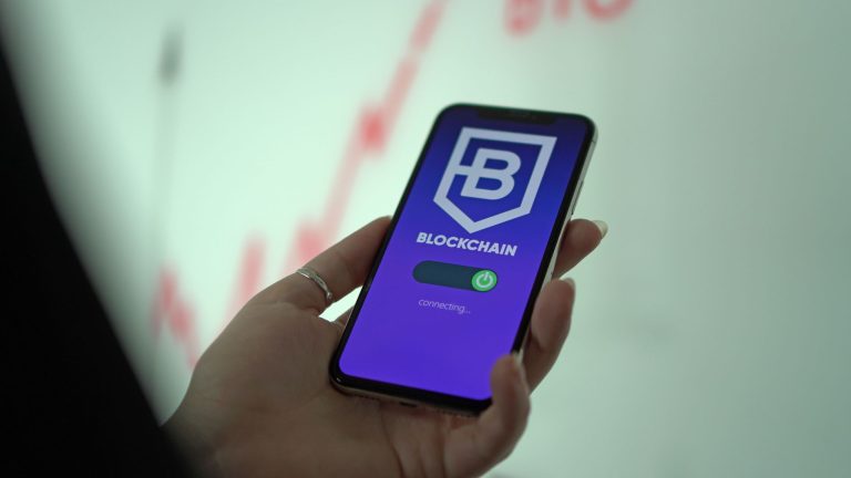 BC amplia comunicação ao Coaf em transferências com ativos virtuais Mão segurando um smartphone que exibe uma carteira digital de criptomoedas baseada em blockchain.